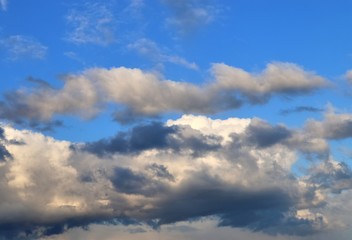 Interesting white and dark mixed cloud formations on a blue sky in spring