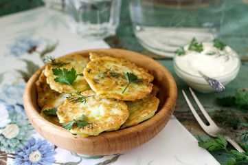 Pancakes with zucchini and sweet corn, served with sour cream, parsley and dill. Vegetarian food.