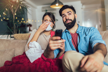 Handsome man taking care of his sick girlfriend lying on the sofa