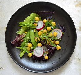 Healthy vegetarian bowl salad with chickpeas, green peas, radish and pistachios, view from above
