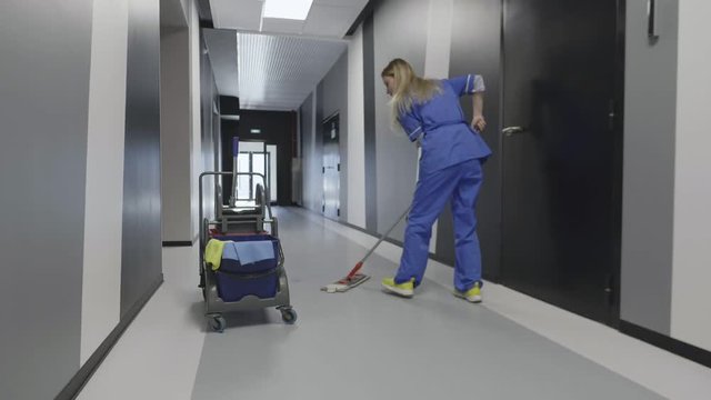 Caucasian janitor woman mopping floor in hallway
