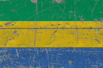 Grunge Gabon flag on old scratched wooden surface. National vintage background.