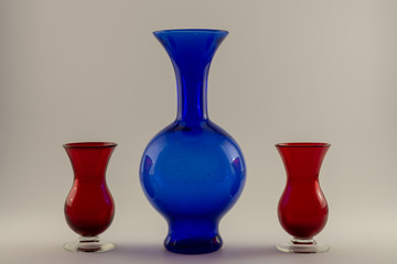single vintage blue vase and two red candle holders, white back ground