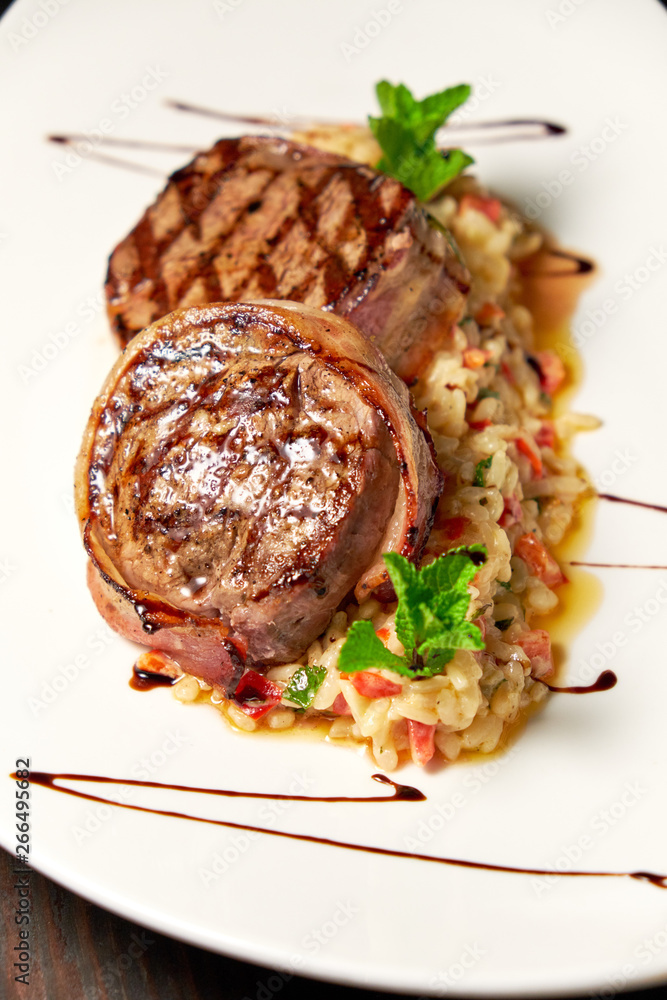 Wall mural Meat medallions in bacon with rice. Dark wooden background. Restaurant menu