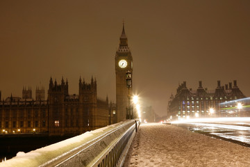 Snow covered Westminster Palace at dawn over dark grey sky.