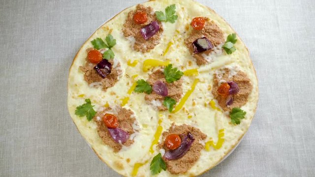 Italian food. Delicious traditional pizza topped with cream sauce, fresh parsley, dried tomatoes, red onion, parmesan cheese, bell pepper, minced beef meat, cumin seeds. Slow motion. HD