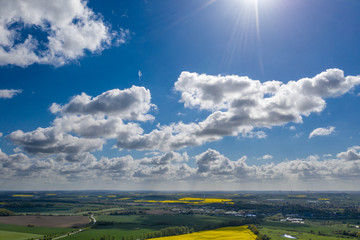 Obraz premium a dreamlike blue sky with white sheep clouds over green and yellow fields