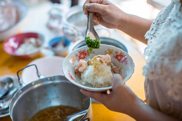 Boiled rice with seafood, shrimp, squid and pork topped by coriander and Celery on the white bowl. Thai fusion breakfast set. image for background, copy space, illustration and menu list.