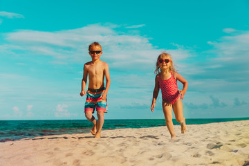 happy cute little boy and girl running at beach