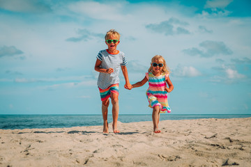 happy cute little boy and girl running at beach