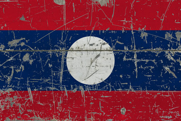Grunge Laos flag on old scratched wooden surface. National vintage background.