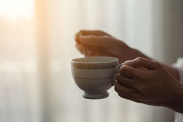 Hand holding a cup of coffee and use a coffee spoon 