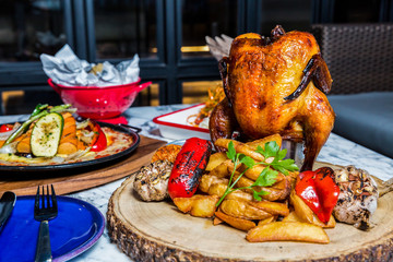 baked chicken in garlic with baked potatoes, sauce , tomatoes on wooden background