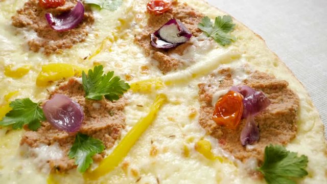Italian food. Delicious traditional pizza topped with cream sauce, fresh parsley, dried tomatoes, red onion, parmesan cheese, bell pepper, minced beef meat, cumin seeds. Slow motion. HD