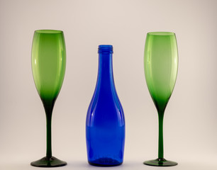 small blue wine bottle and two green glasses on a white back ground