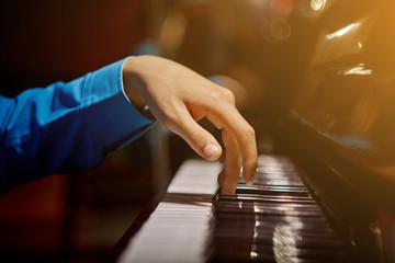 one male hand on the piano. The palm lies on the keys and plays the keyboard instrument in the music school. student learns to play. hands pianist. black dark background