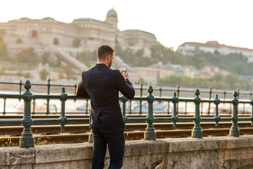 A businessman next to a tramline taking a photo