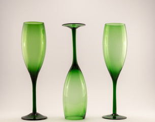 green wine glasses in a row one upside down on a white back ground