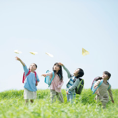 草原で紙飛行機を飛ばす小学生