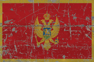 Grunge Montenegro flag on old scratched wooden surface. National vintage background.