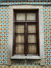 Wooden window of typical portuguese houses, with ceramic tiles on the facade.