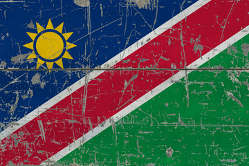 Grunge Namibia flag on old scratched wooden surface. National vintage background.