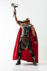 Long hair and muscular male model in leather viking's costume with the big hammer cosplaying Thor...