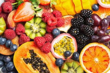 Delicious fruit platter mango pomegranate raspberries papaya oranges passion fruits berries on oval serving plate on dark concrete background, selective focus, top view