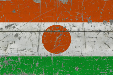 Grunge Niger flag on old scratched wooden surface. National vintage background.