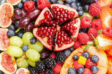 Delicious fruit platter mango papaya oranges passion fruits berries on round serving plate on dark concrete background, overhead view, selective focus, copy space