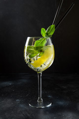 Mojito cocktail or lemonade with mint leaves in glass on black table. Close up. Summer refreshing drink.
