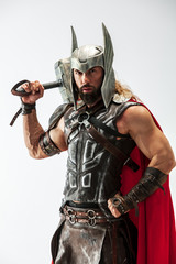 Long hair and muscular male model in leather viking's costume with the big hammer cosplaying Thor...