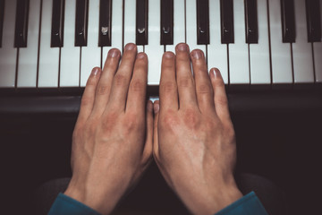 two male hands on the piano. palms lie on the keys and play the keyboard instrument in the music...