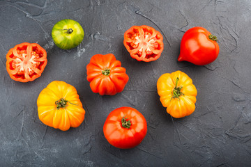 Selection of organic large heirloom tomatoes on dark blue concrete background, top view, selective focus