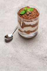 portion of Classic tiramisu dessert in a glass on concrete background