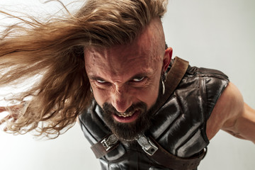 God of thunder. Blonde long hair and muscular male model in leather viking's costume with the big hammer cosplaying Thor isolated on white studio background. Fantasy warrior, antique battle concept.