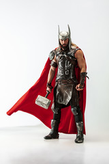 Long hair and muscular male model in leather viking's costume with the big hammer cosplaying Thor...