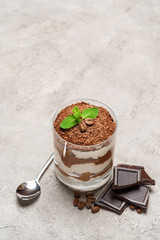 portion of Classic tiramisu dessert in a glass on concrete background