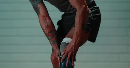 Athletic man puts on prostetic leg in slowmotion stands and is ready for sport activity. Strong amputee with tattoos does not let any disability stop him. Shot in 4k.mov - Powered by Adobe