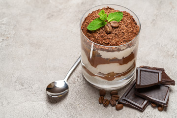 portion of Classic tiramisu dessert in a glass on concrete background