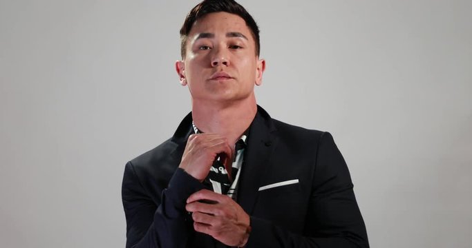 Attractive Asian model in slowmotion turns and changes poses during an ecommerce fasion photoshoot for a website or social media in front of a white background with jacket. Shot in 4k.mov