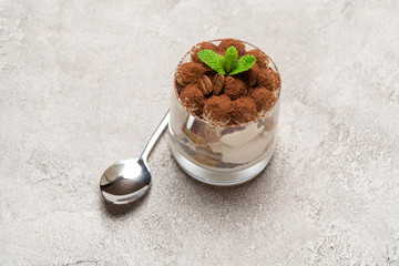 portion of Classic tiramisu dessert in a glass on concrete background