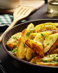 Baked potatoes with spices and parsley on a black background