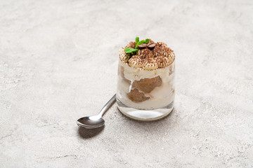 portion of Classic tiramisu dessert in a glass on concrete background