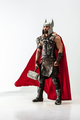 Long hair and muscular male model in leather viking's costume with the big hammer cosplaying Thor...