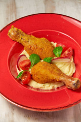 Chicken legs on the side with mashed potatoes. Light wooden background. Restaurant menu