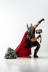 Long hair and muscular male model in leather viking's costume with the big hammer cosplaying Thor...