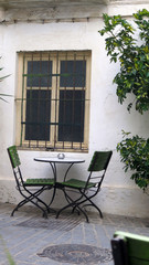 Fototapeta na wymiar Spindly chairs in shady secluded courtyard
