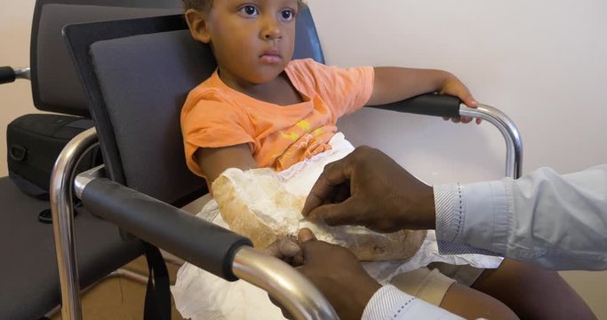 A young mixed raced child having a cast removed from his arm after a broken bone has healed.