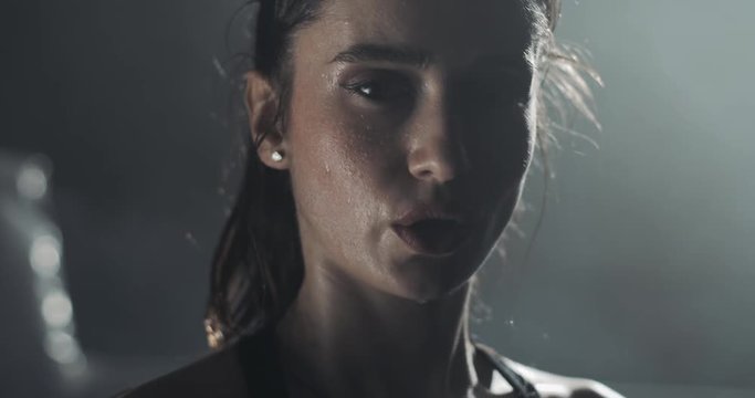 Portrait of tired female boxer standing on the boxing ring and looking at the camera